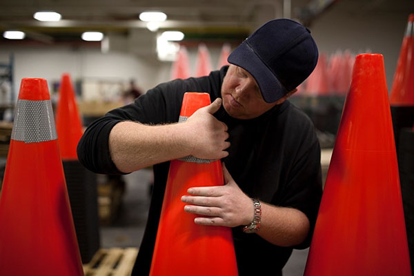 A man placing reflective tape to a stack of pylons 