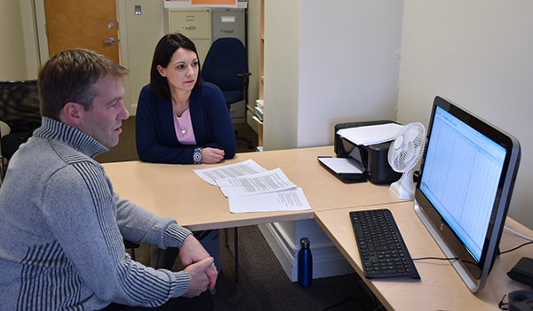 Two researchers studying data on a computer screen