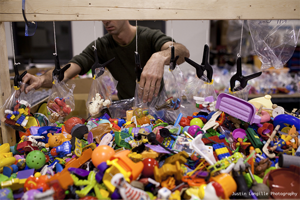 A pile of toys and a man placing them in plastic bags 